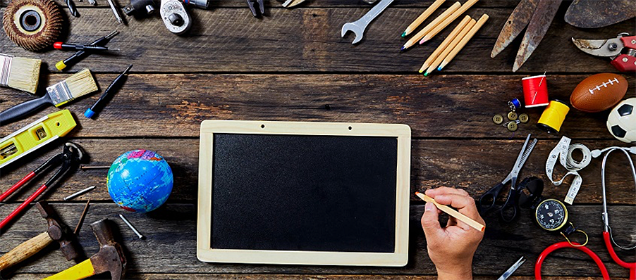 Image of tablet computer with a hand holding a stylus, surrounded by tools on a workbench.